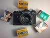 A film camera with various film boxes around it.