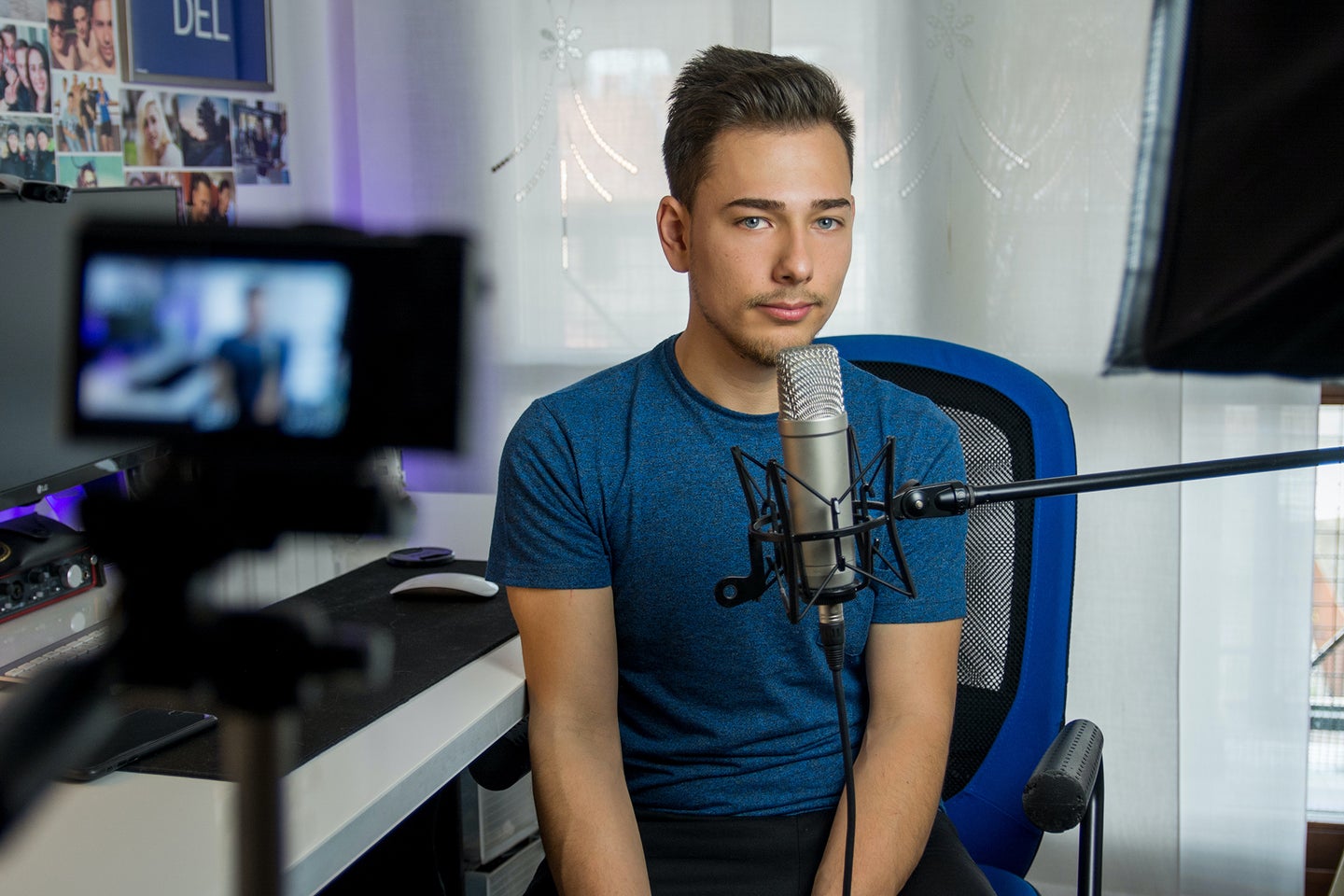 man in front of the best camera for streaming, with a microphone, sitting in a blue chair