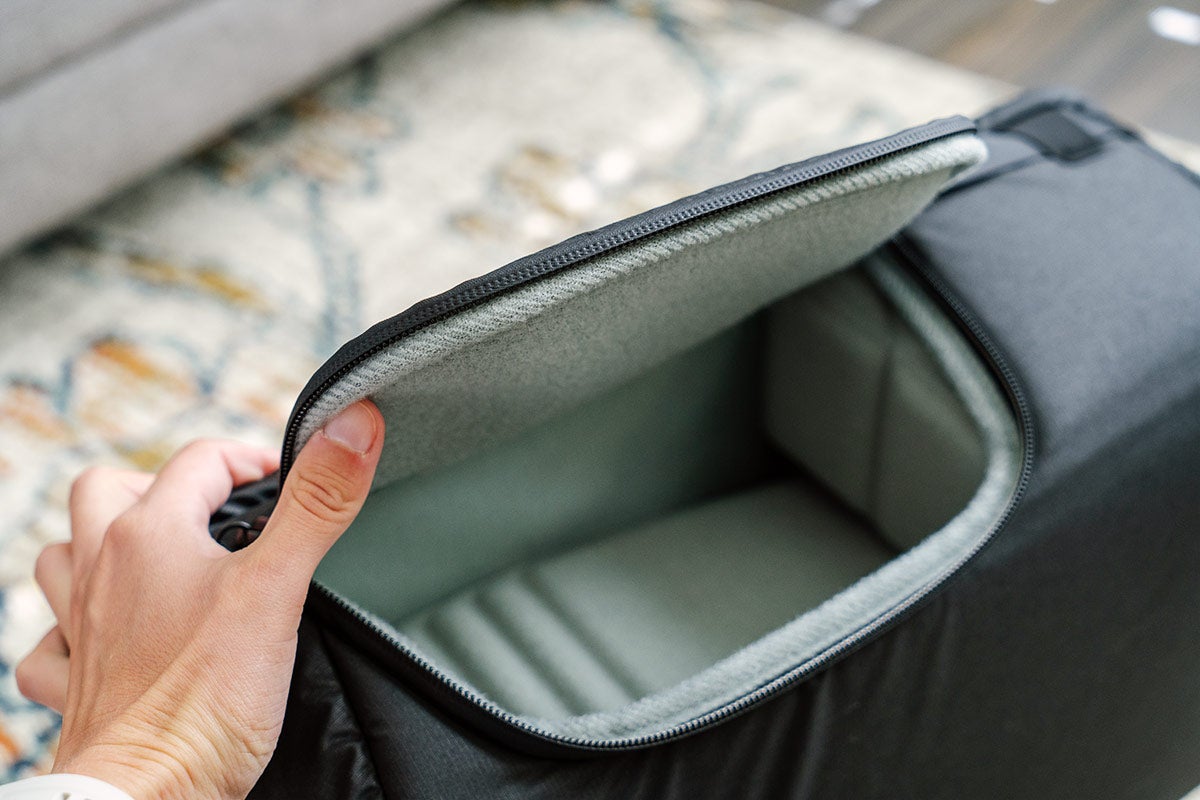 A hand holds the side access flap of the Large Camera Cube V2 open. 